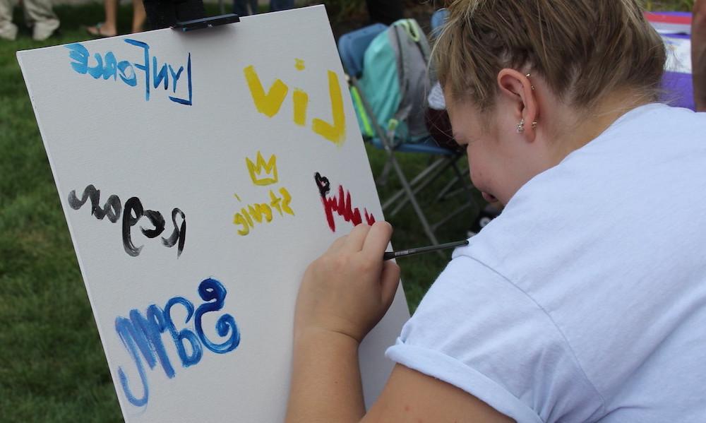 Student paints a sign for art club on Fenner Quadrangle